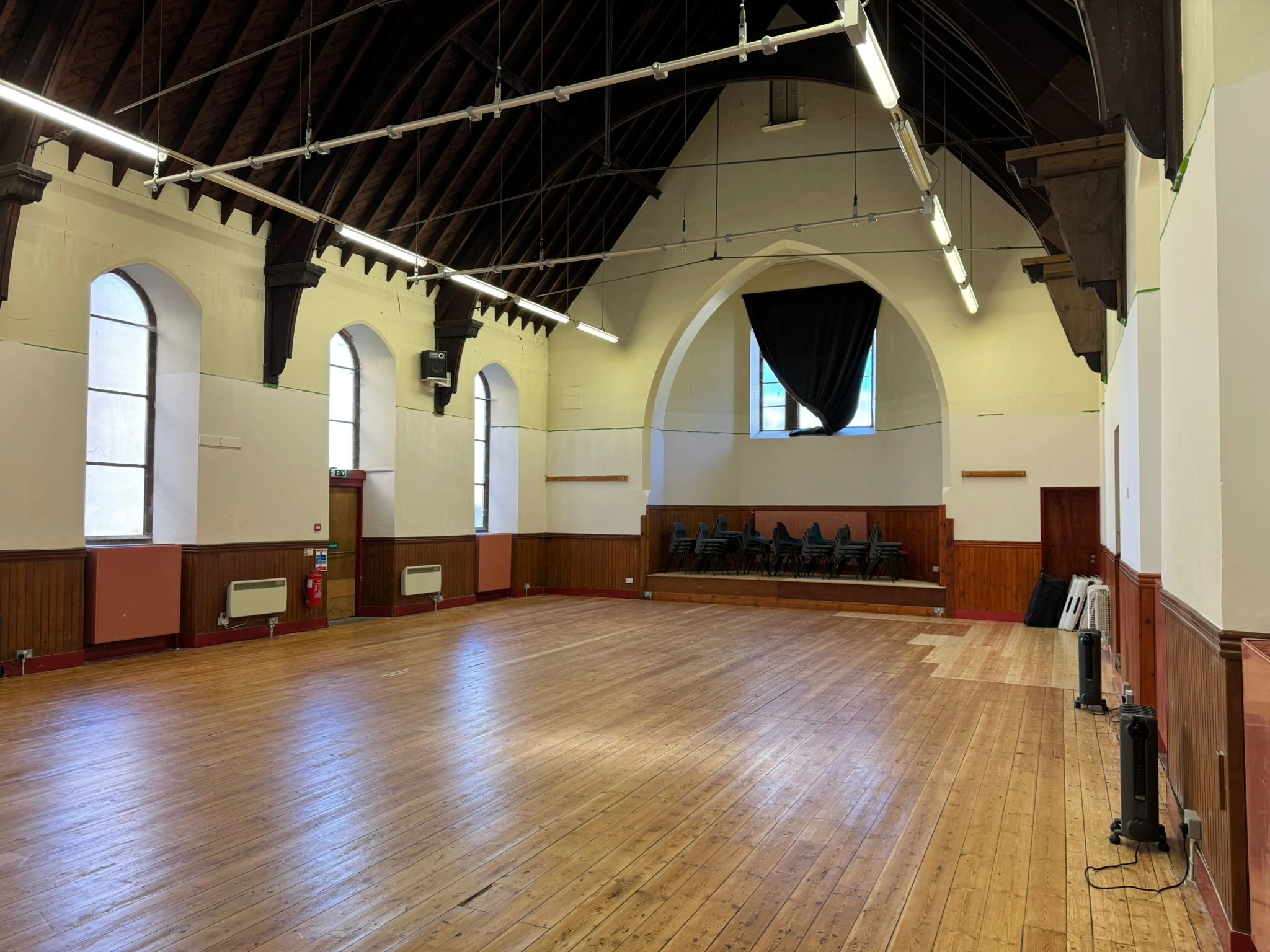 The North Hall interior — a large open space with polished wooden floors, high vaulted ceilings with exposed dark timber beams, and tall arched windows